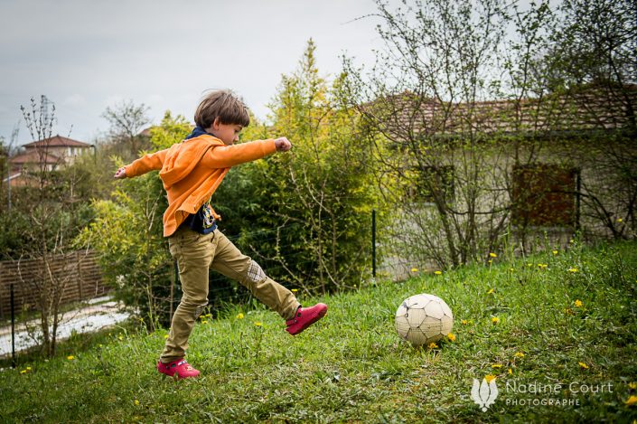reportage-lyon-famille-enfants-nadine-court Image d'un enfant jouant au ballon dans son jardin - reportage documentaire de famille